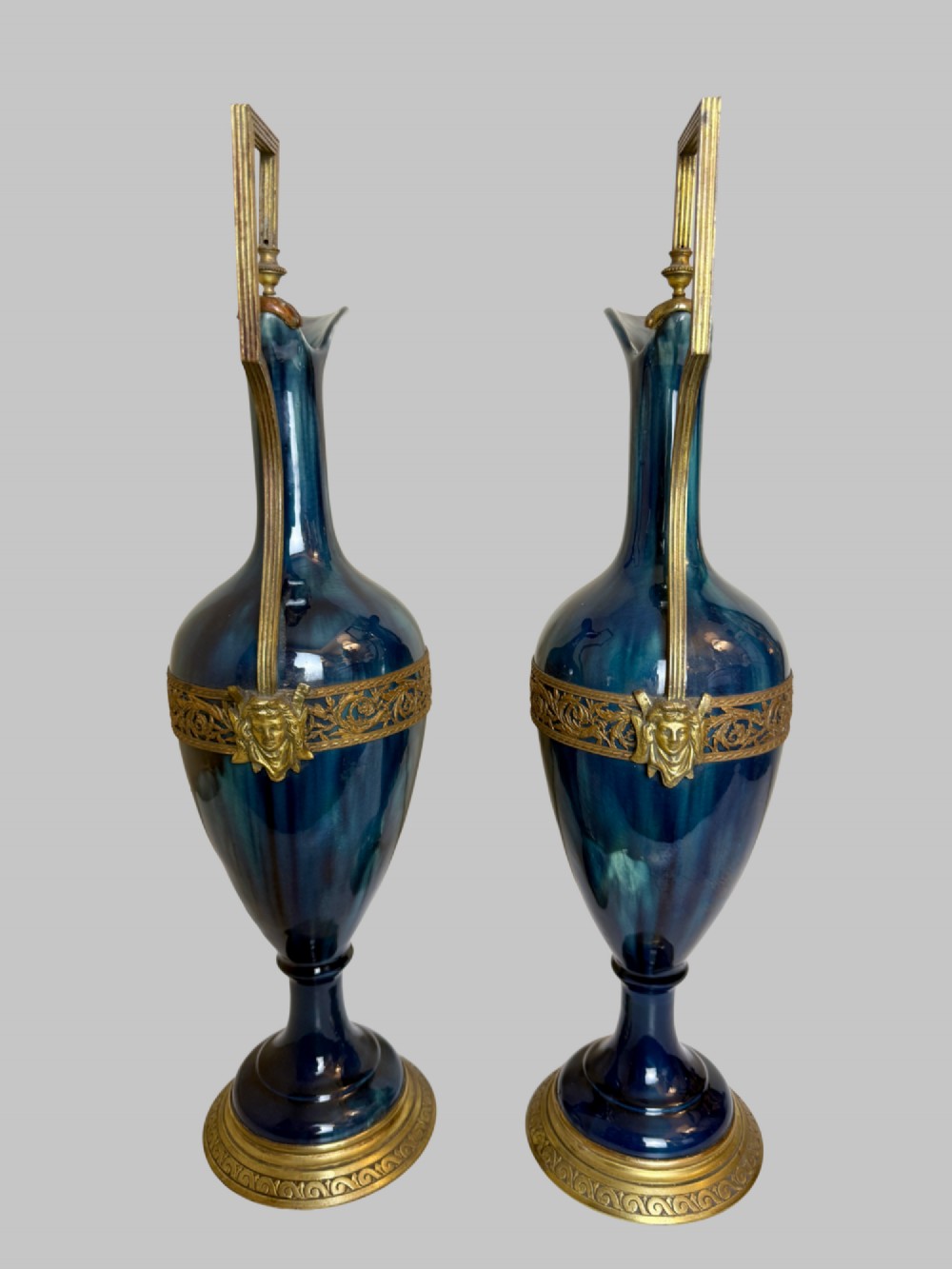 A pair of slender blue porcelain ewers featuring decorative gilt bronze mounts, angular handles, and flared spouts. View VII