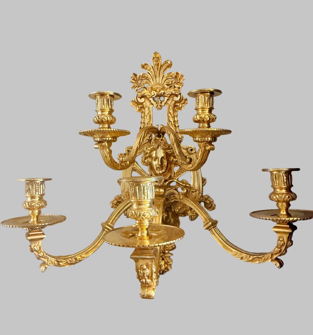 A pair of late nineteenth-century French gilt bronze five-light wall sconces featuring ornate rococo scrollwork and mascaron motifs. View II