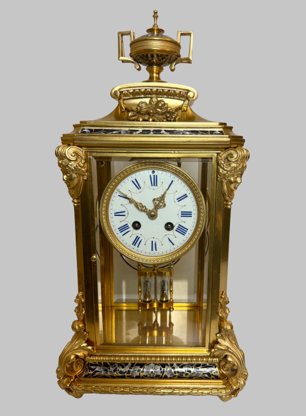 A late 19th-century French clock garniture featuring a gilt bronze mantel clock flanked by two matching champleve enamel side urns. View II