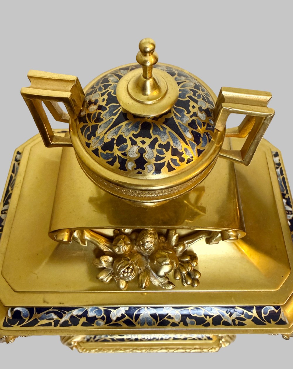 A late 19th-century French clock garniture featuring a gilt bronze mantel clock flanked by two matching champleve enamel side urns. View V