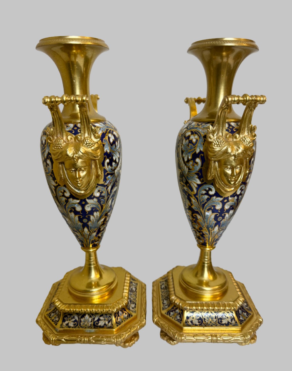A late 19th-century French clock garniture featuring a gilt bronze mantel clock flanked by two matching champleve enamel side urns. View X
