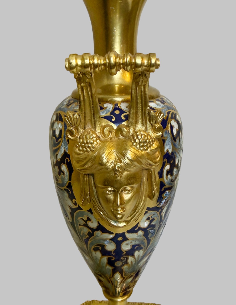 A late 19th-century French clock garniture featuring a gilt bronze mantel clock flanked by two matching champleve enamel side urns. View XII