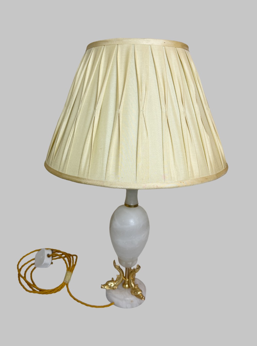 A pair of French onyx urn-shaped table lamps featuring gilt bronze dolphin feet and cream pleated shades. View II