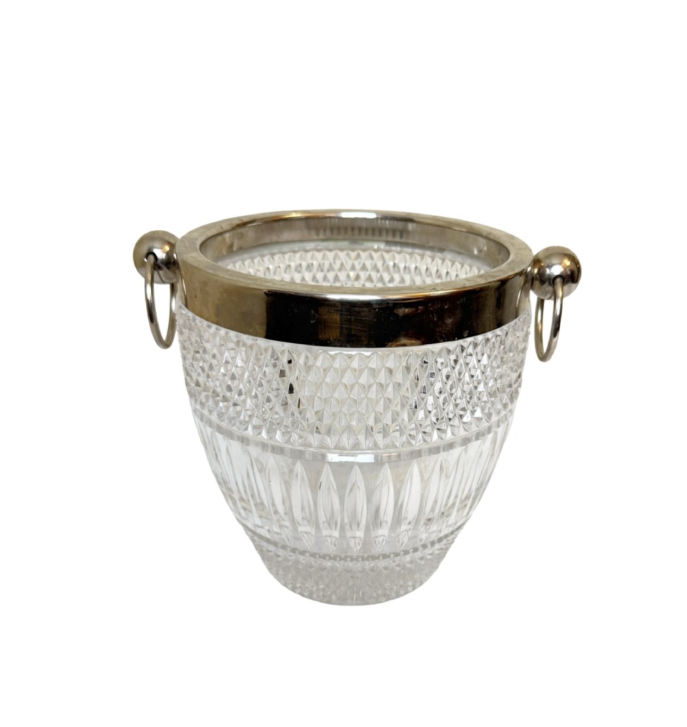 A French circa 1920 clear cut crystal ice bucket featuring geometric diamond facet cuts, a silver-plated rim, and round drop-ring side handles.