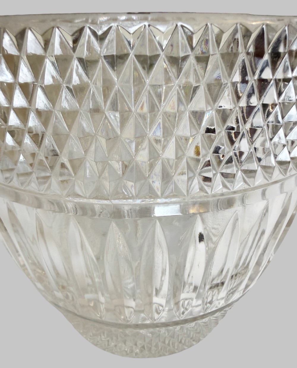 A French circa 1920 clear cut crystal ice bucket featuring geometric diamond facet cuts, a silver-plated rim, and round drop-ring side handles. View V