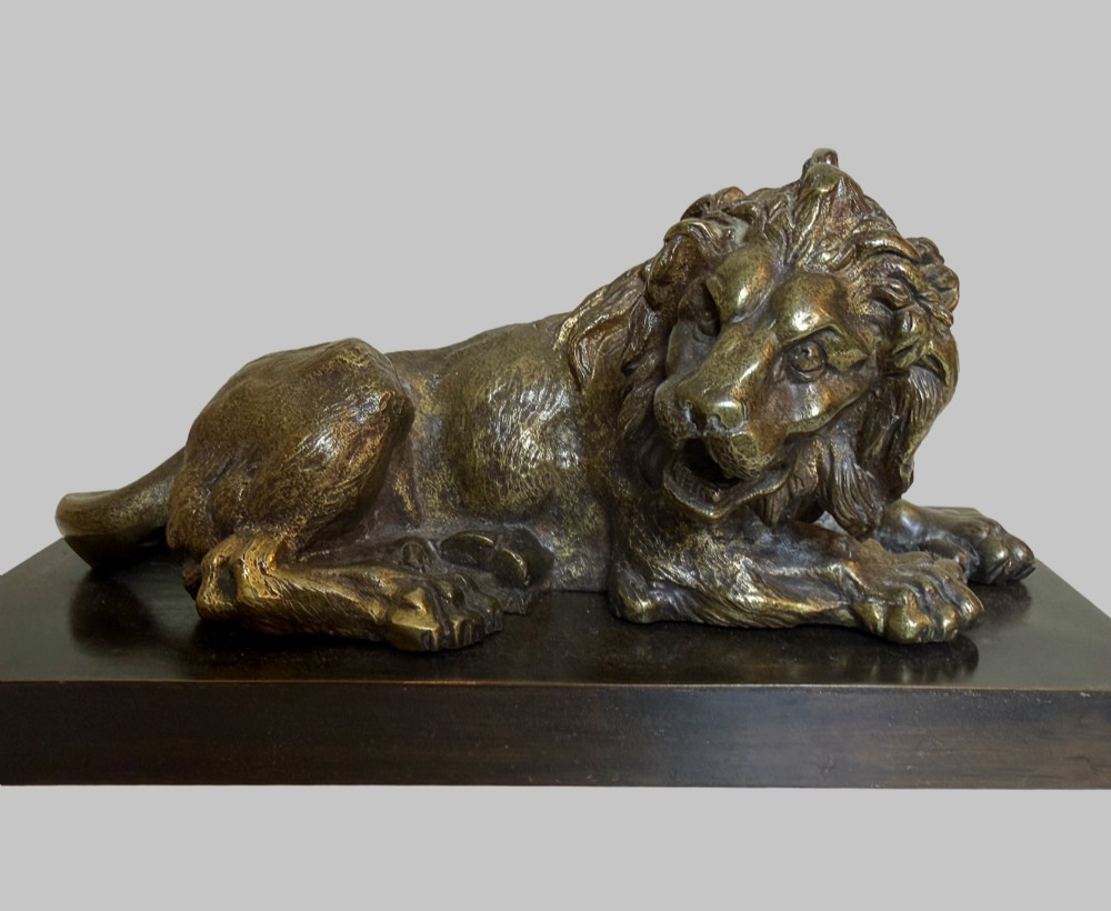 A pair of late 19th-century patinated bronze sculptures depicting recumbent lions resting on dark rectangular marble bases. View III
