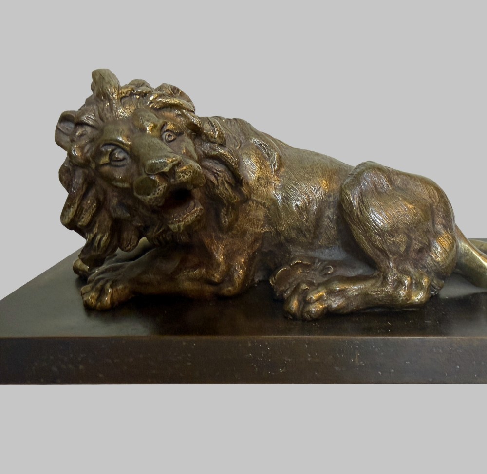 A pair of late 19th-century patinated bronze sculptures depicting recumbent lions resting on dark rectangular marble bases. View IV