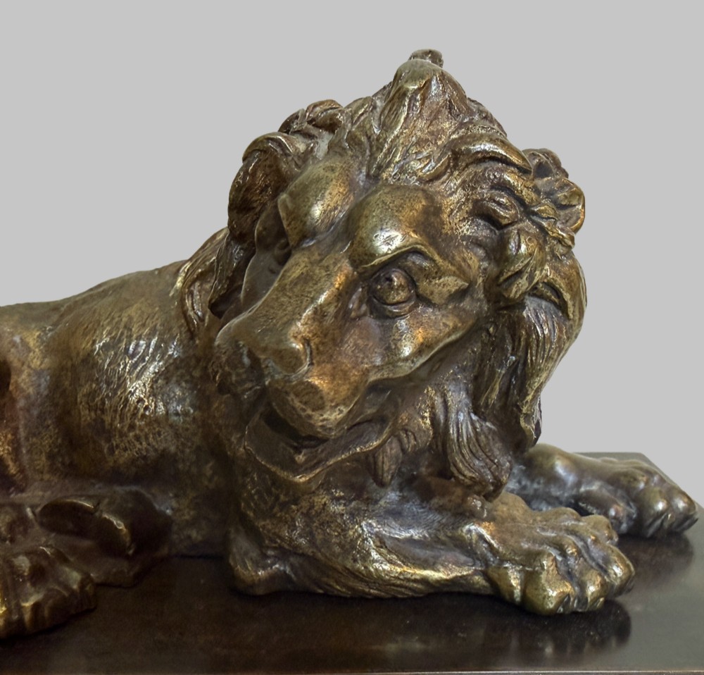 A pair of late 19th-century patinated bronze sculptures depicting recumbent lions resting on dark rectangular marble bases. View V
