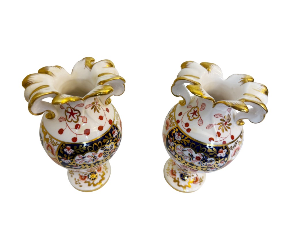 A pair of 19th-century Spode porcelain twin-handled vases decorated in a cobalt blue, iron red, and gold leaf Imari pattern.