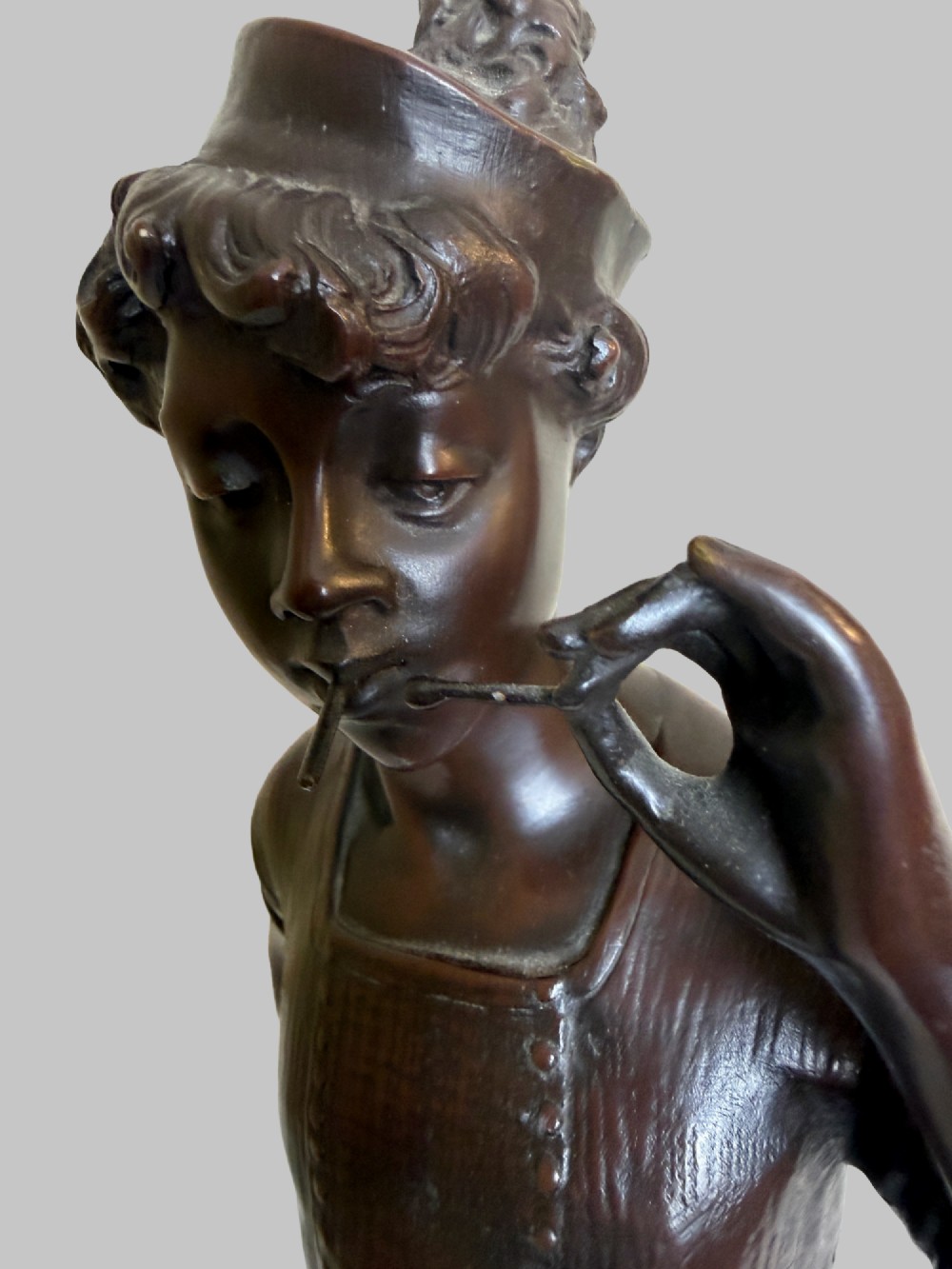 A dark patinated bronze statue of a young man smoking a cigarette while holding a croquet mallet on a round base with croquet balls. View V