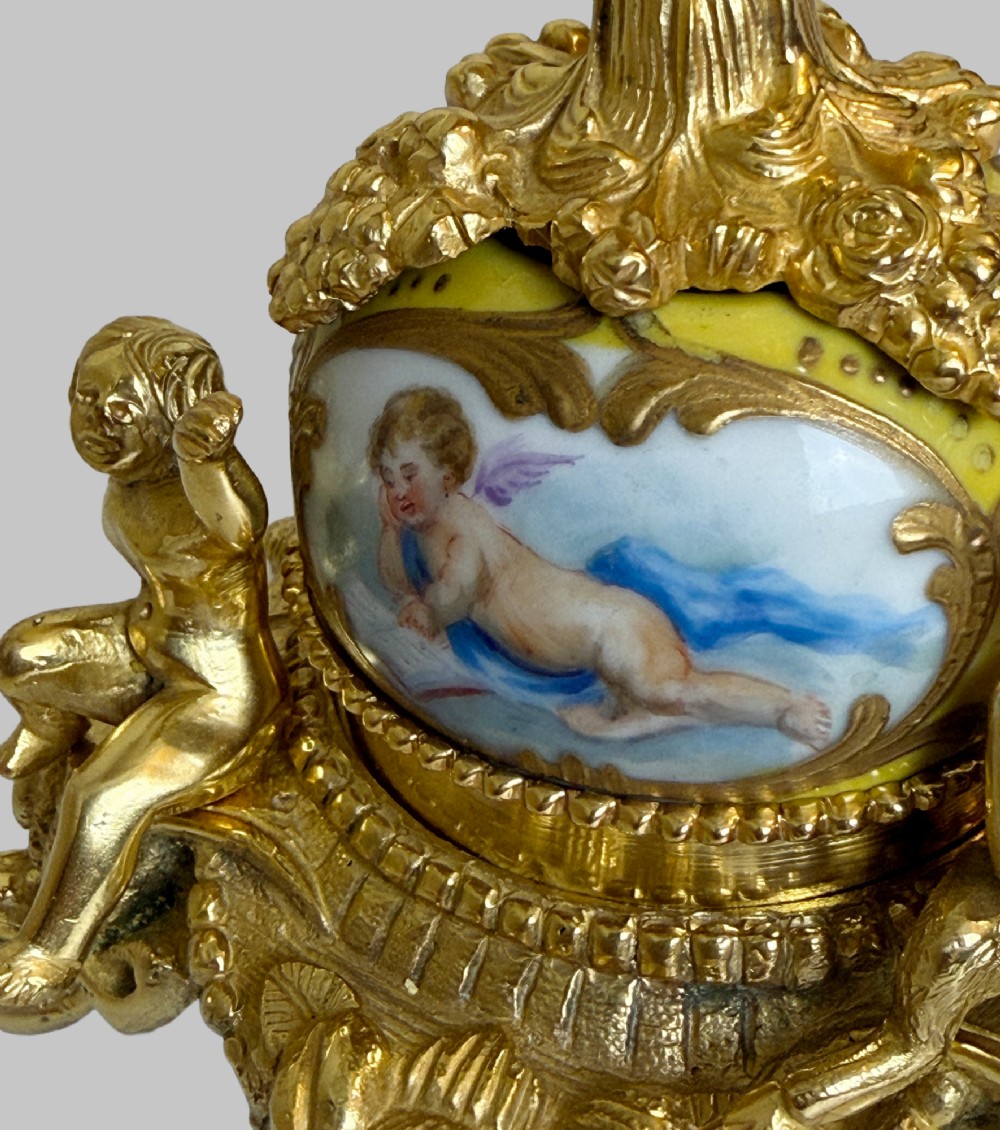 An ornate gilt bronze centrepiece dish featuring a cut crystal bowl, hand-painted porcelain cherub panels, and three seated bronze putti figures on a scrolled base. View IV