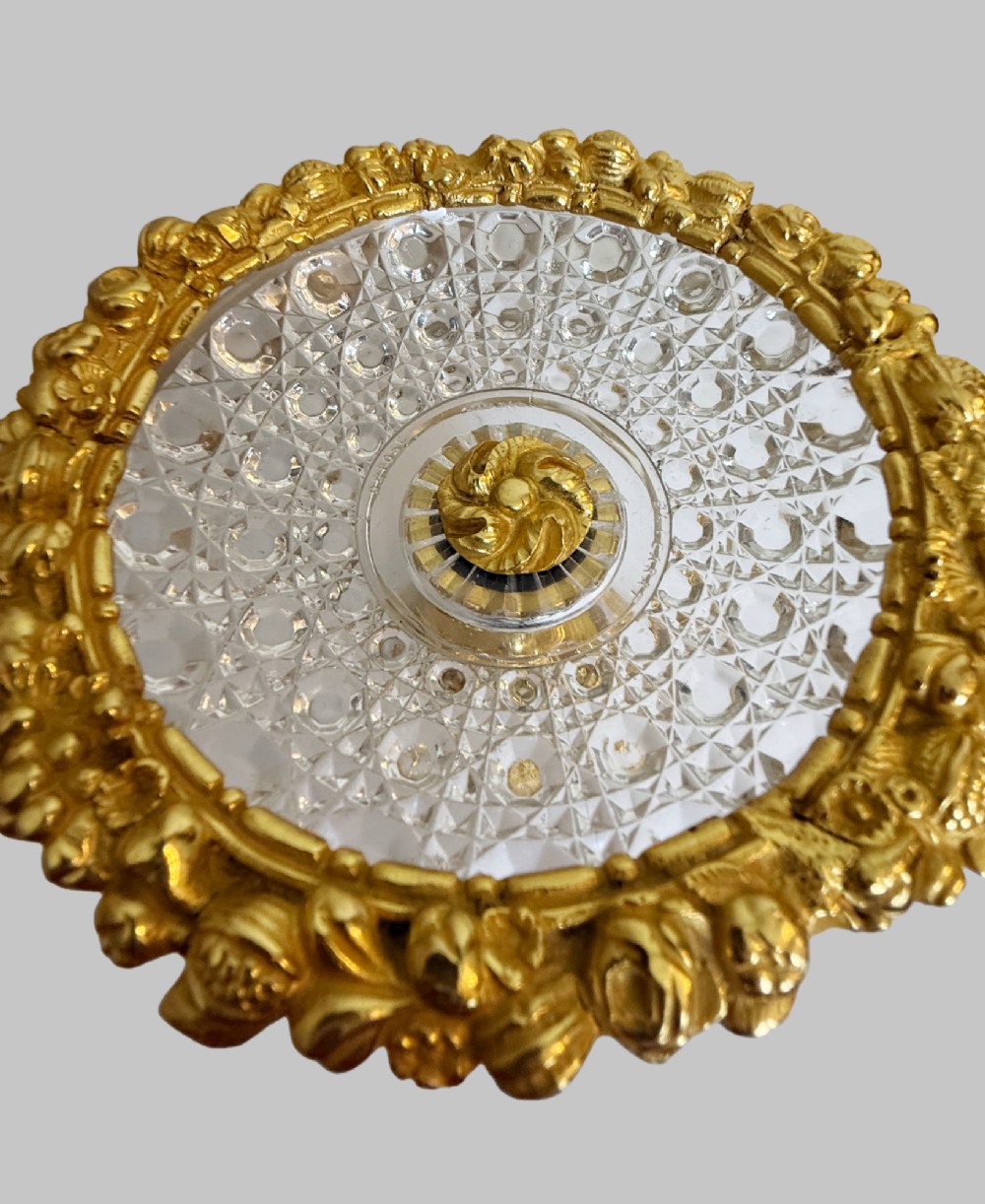 An ornate gilt bronze centrepiece dish featuring a cut crystal bowl, hand-painted porcelain cherub panels, and three seated bronze putti figures on a scrolled base. View VI