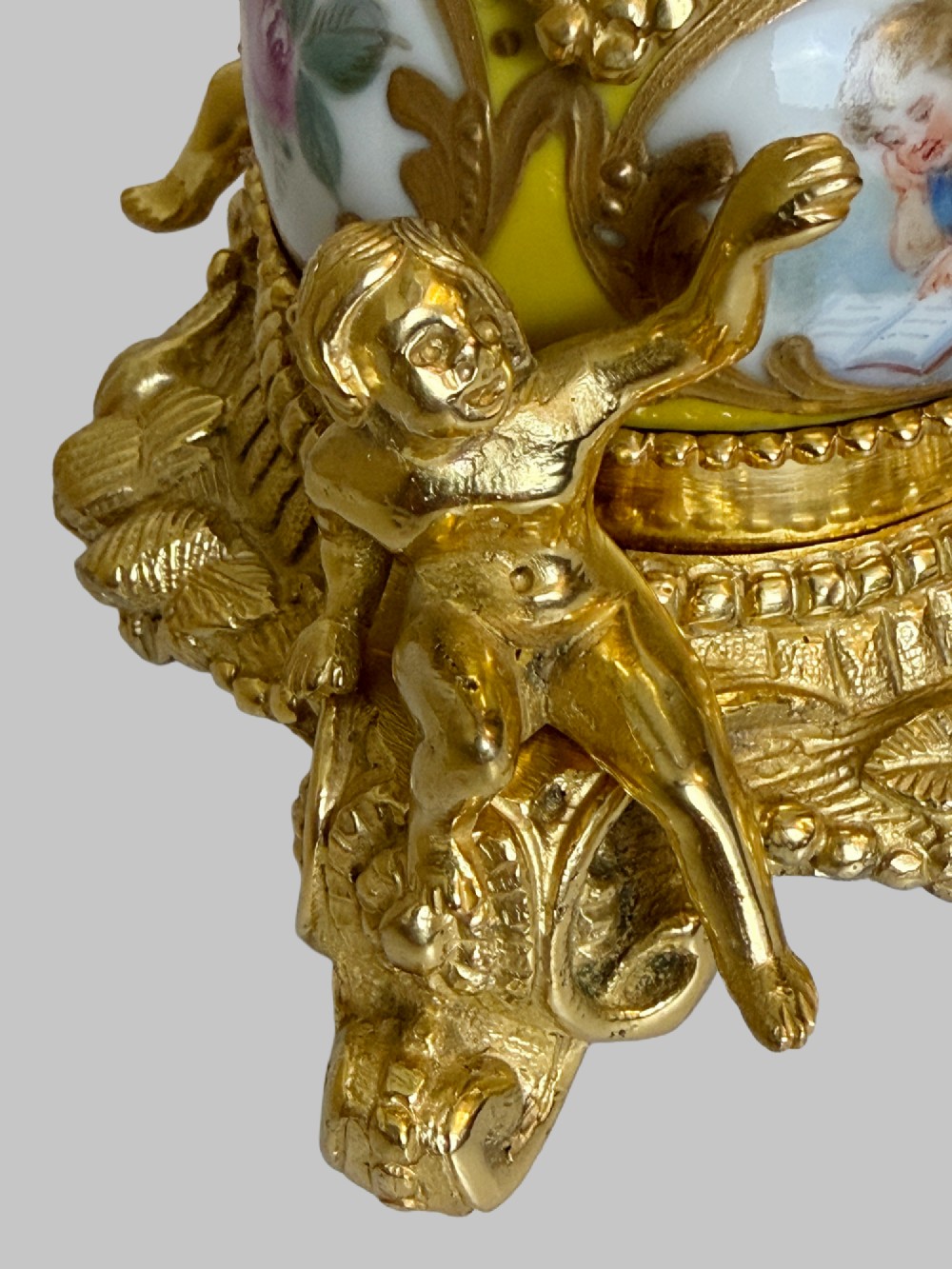 An ornate gilt bronze centrepiece dish featuring a cut crystal bowl, hand-painted porcelain cherub panels, and three seated bronze putti figures on a scrolled base. View VII