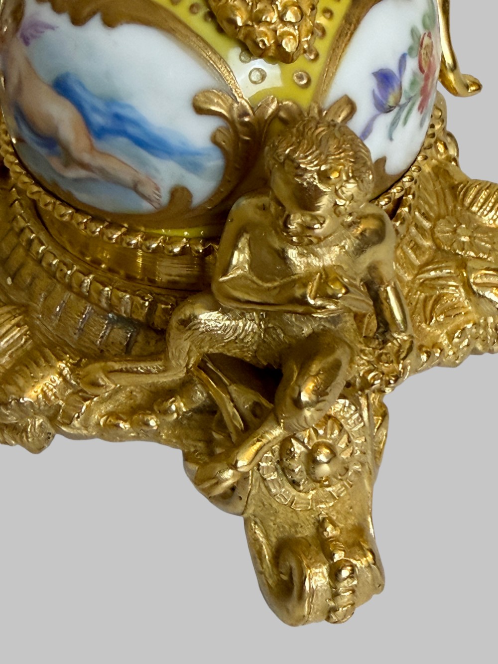 An ornate gilt bronze centrepiece dish featuring a cut crystal bowl, hand-painted porcelain cherub panels, and three seated bronze putti figures on a scrolled base. View VIII