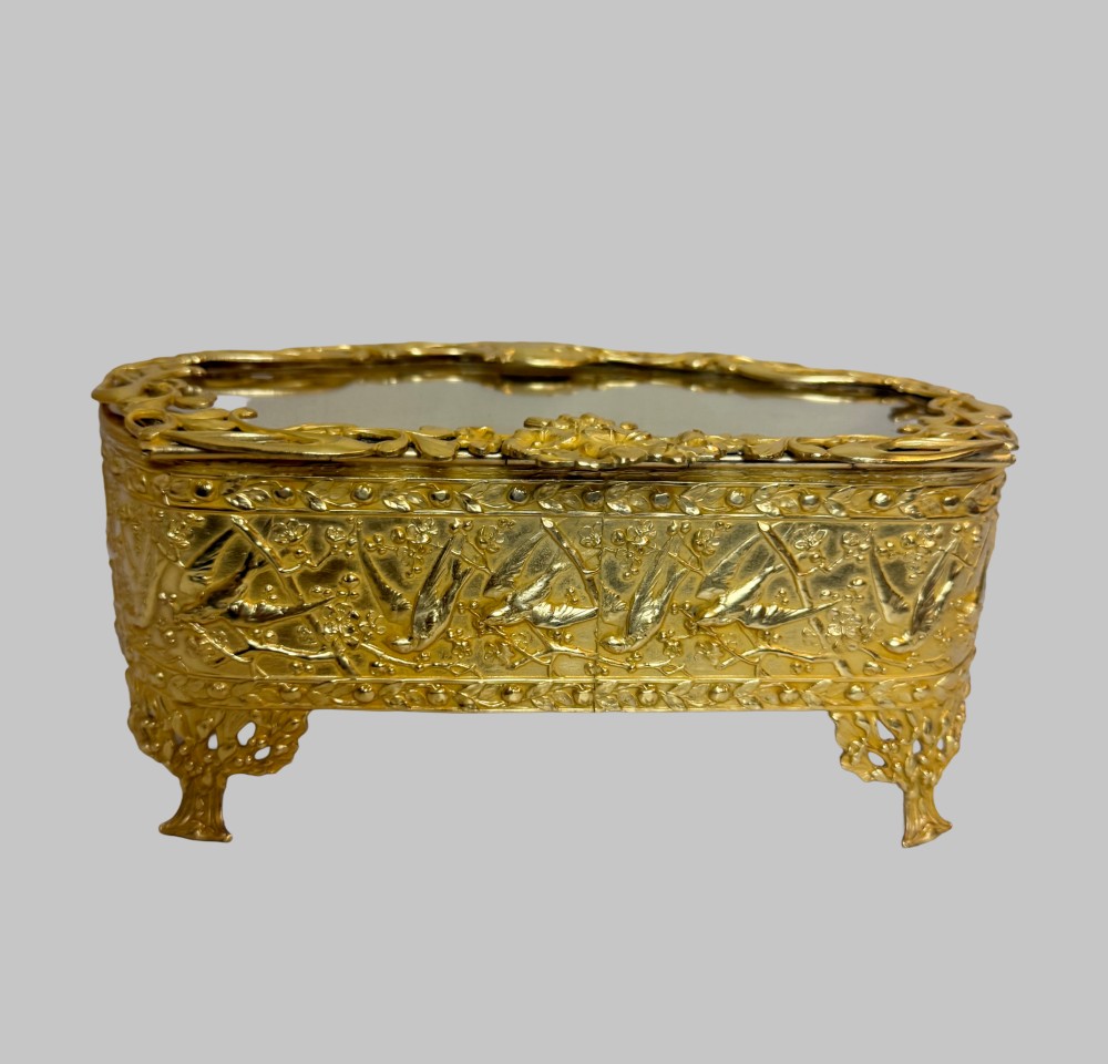 An Art Nouveau gilt bronze jewellery box featuring embossed bird motifs and a bevelled glass lid. View V