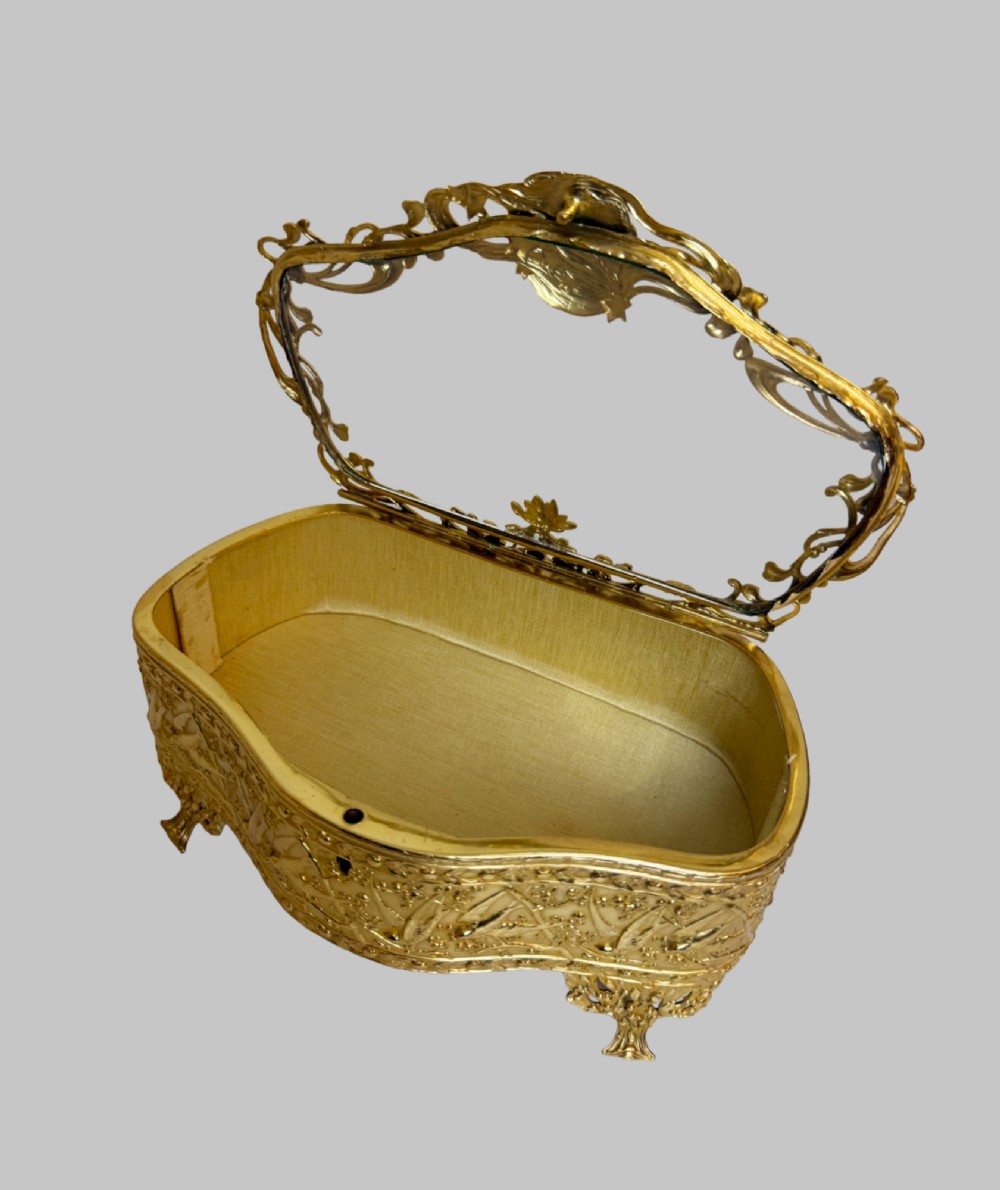 An Art Nouveau gilt bronze jewellery box featuring embossed bird motifs and a bevelled glass lid. View VIII