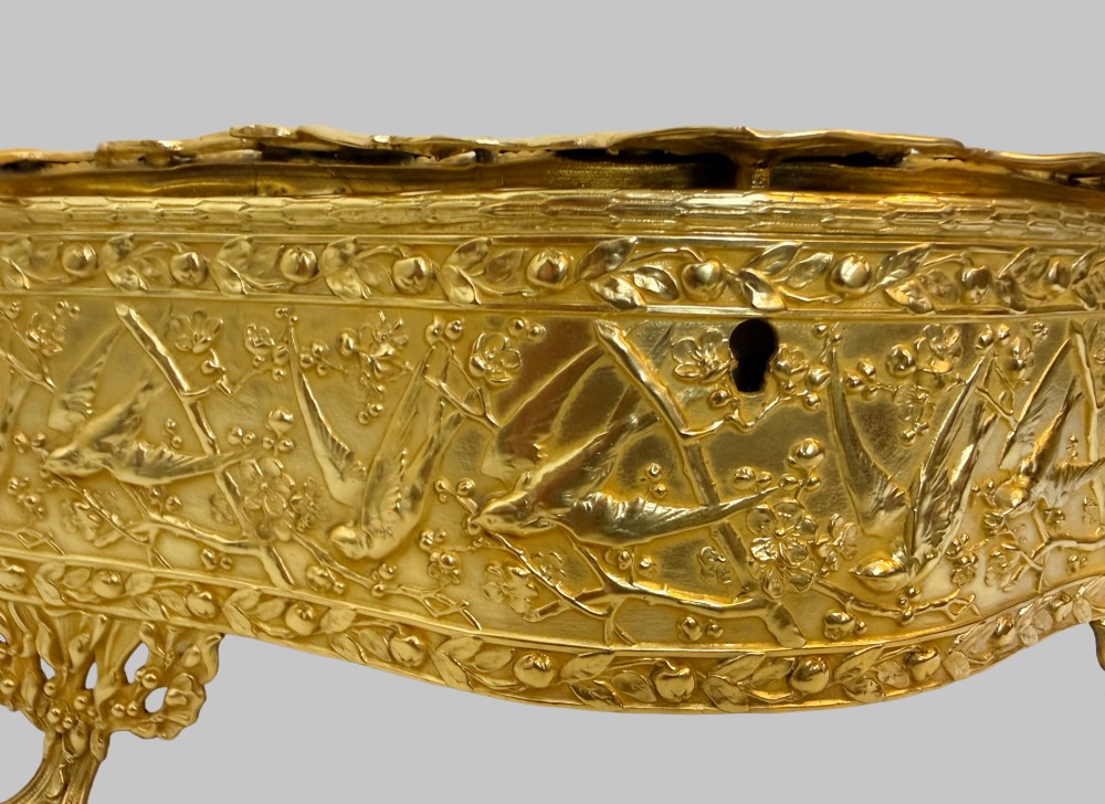 An Art Nouveau gilt bronze jewellery box featuring embossed bird motifs and a bevelled glass lid. View IX