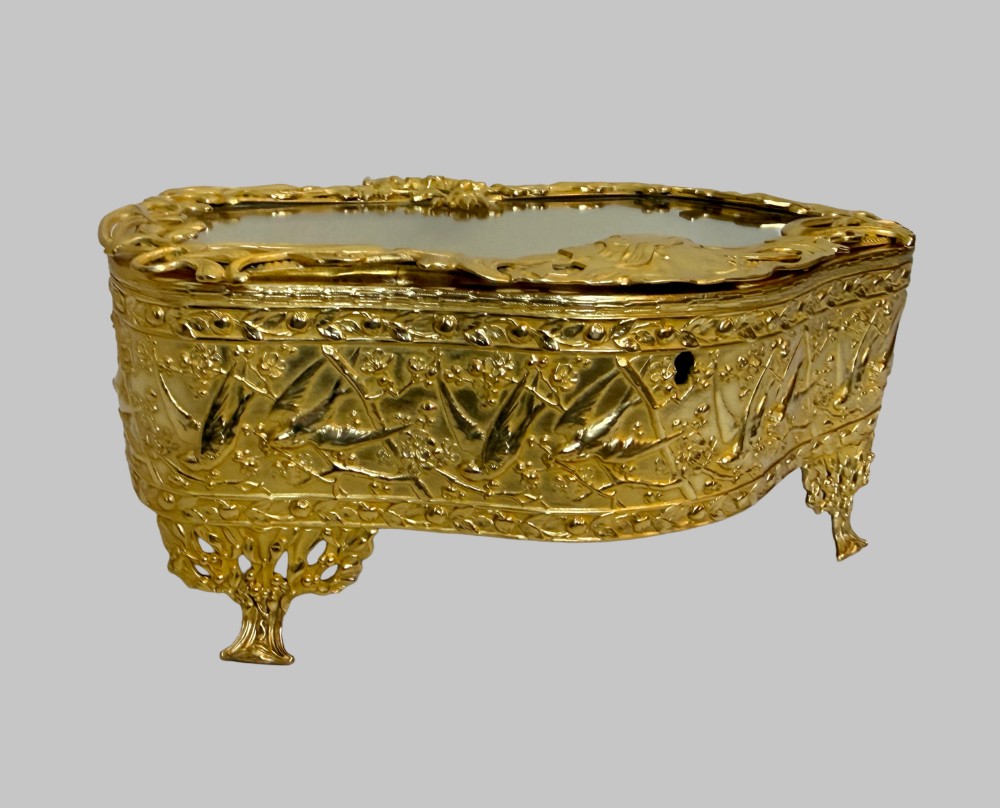 An Art Nouveau gilt bronze jewellery box featuring embossed bird motifs and a bevelled glass lid. View X
