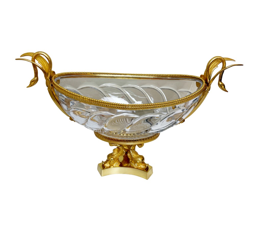 A 19th-century boat-shaped cut-crystal bowl with gilt-bronze swan-form handles and a pedestal base supported by gilt dolphins.