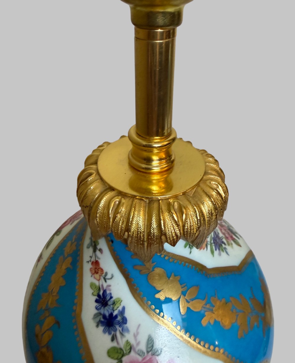 A pair of 19th-century Sevres style table lamps featuring spiral turquoise blue and white porcelain bodies decorated with painted flowers and gold gilding, set on ornate gilt bronze bases. View III