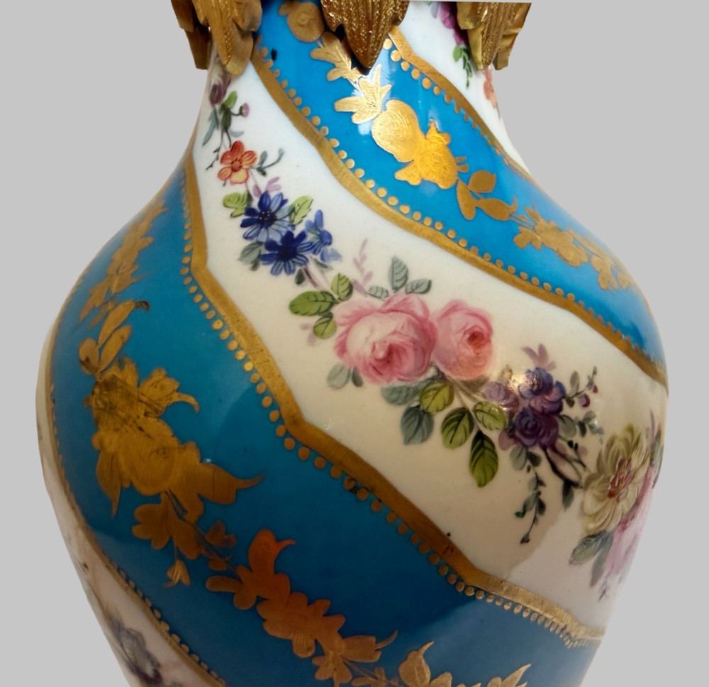 A pair of 19th-century Sevres style table lamps featuring spiral turquoise blue and white porcelain bodies decorated with painted flowers and gold gilding, set on ornate gilt bronze bases. View VI