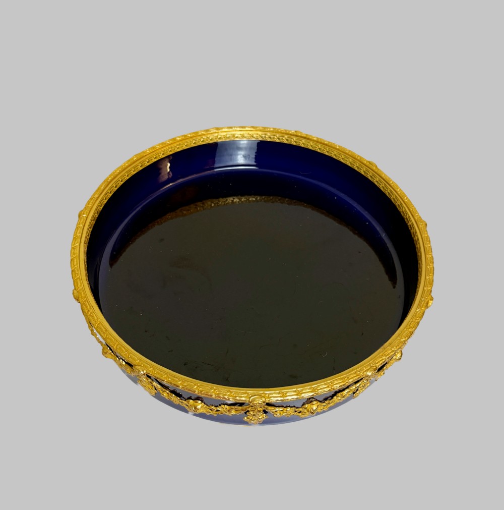 A deep cobalt blue porcelain bowl raised on a pedestal base with ornate gilt bronze floral swags and a chased rim. View III
