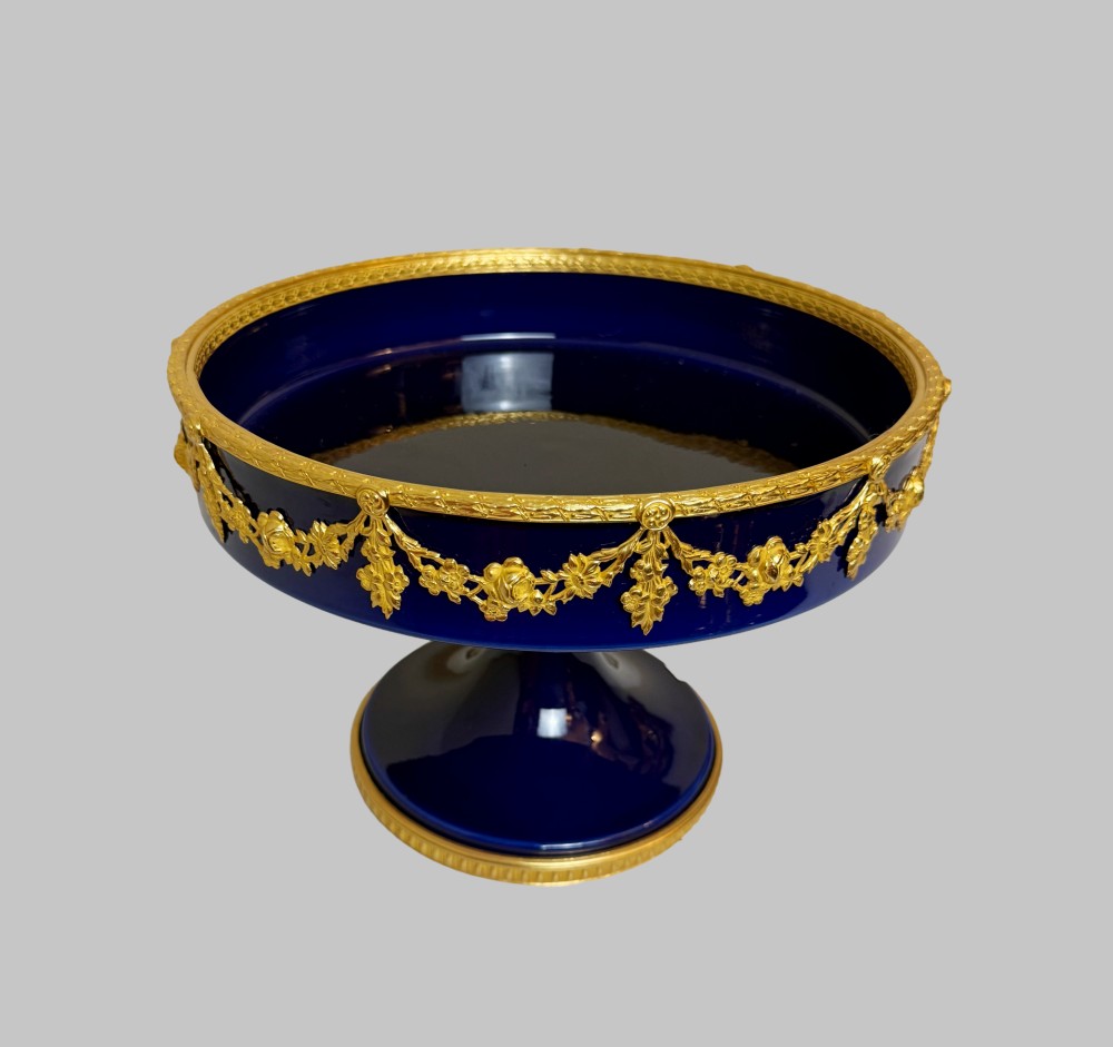 A deep cobalt blue porcelain bowl raised on a pedestal base with ornate gilt bronze floral swags and a chased rim. View IV