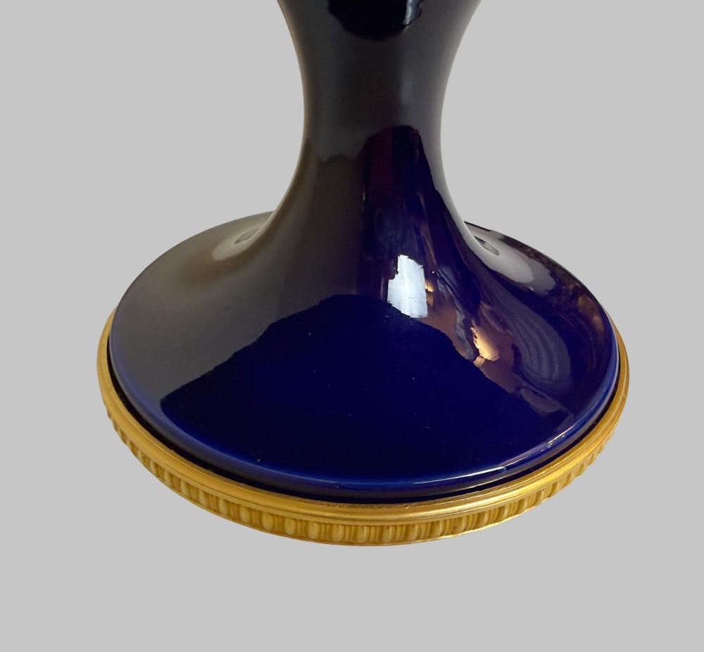 A deep cobalt blue porcelain bowl raised on a pedestal base with ornate gilt bronze floral swags and a chased rim. View V