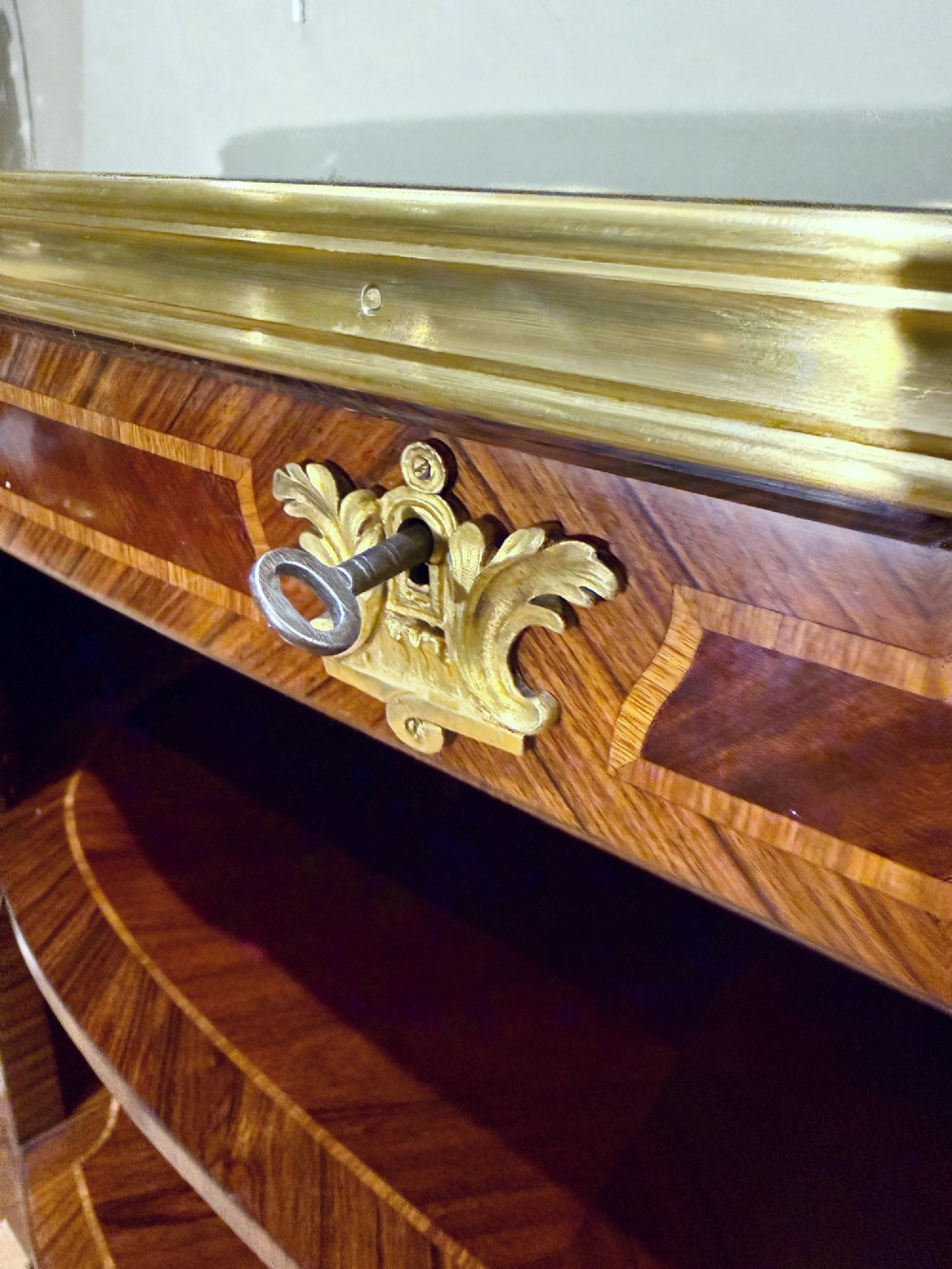 A late 19th-century French Louis XV style demilune open bookcase featuring marquetry wood veneer, gilt-bronze ormolu mounts, open shelving, and a glass vitrine top. View VI