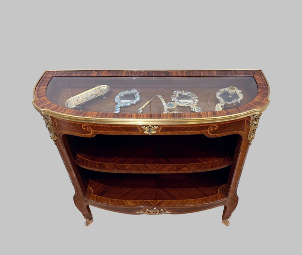 A late 19th-century French Louis XV style demilune open bookcase featuring marquetry wood veneer, gilt-bronze ormolu mounts, open shelving, and a glass vitrine top. View IX