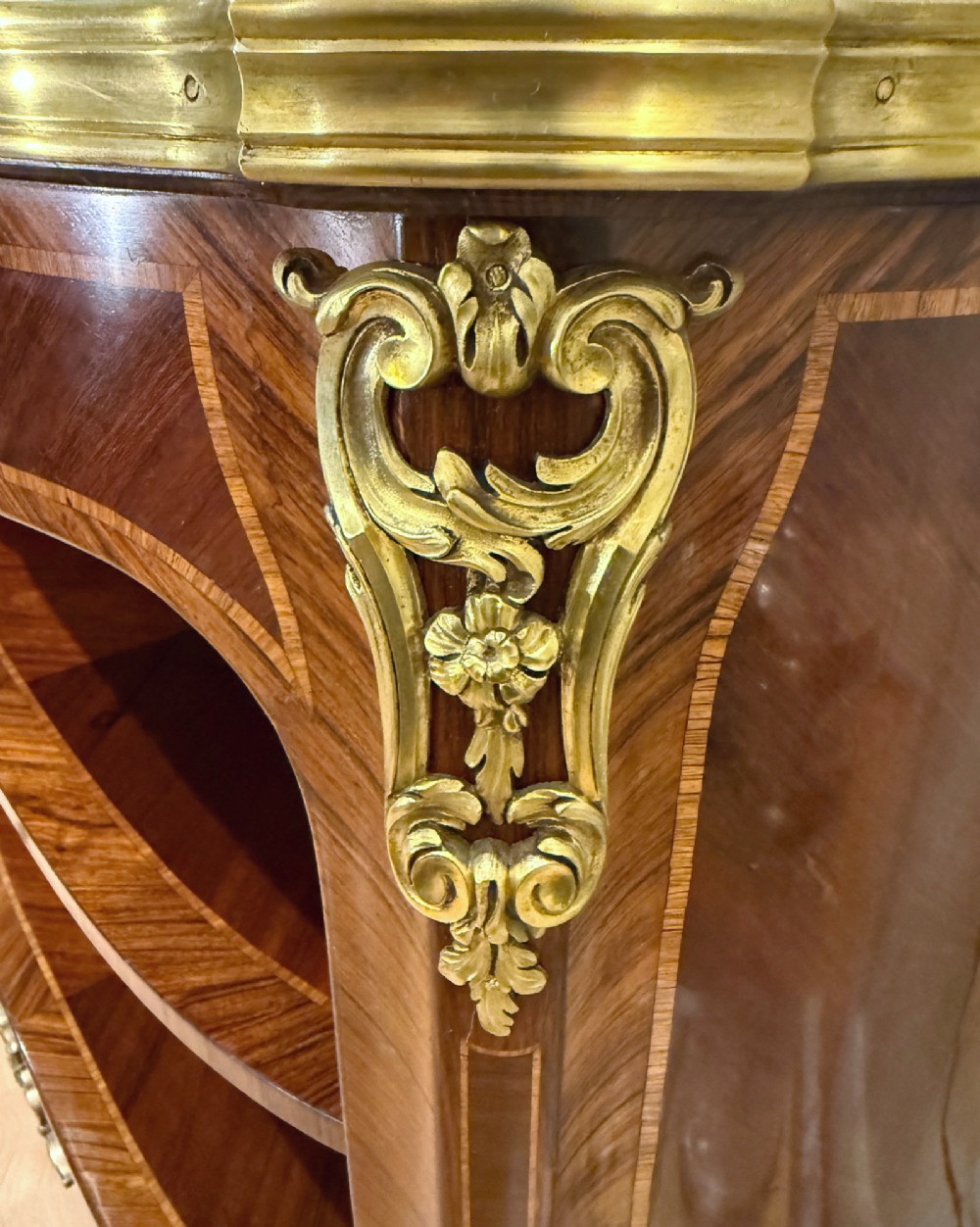 A late 19th-century French Louis XV style demilune open bookcase featuring marquetry wood veneer, gilt-bronze ormolu mounts, open shelving, and a glass vitrine top. View X