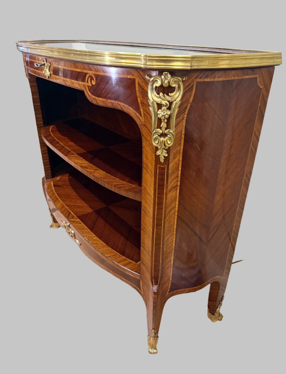 A late 19th-century French Louis XV style demilune open bookcase featuring marquetry wood veneer, gilt-bronze ormolu mounts, open shelving, and a glass vitrine top. View XI