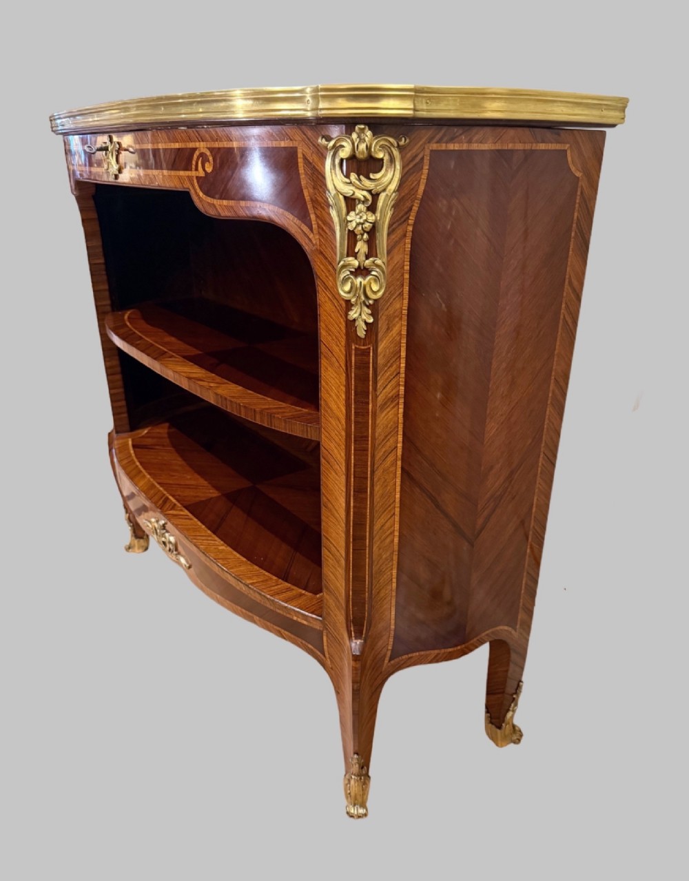 A late 19th-century French Louis XV style demilune open bookcase featuring marquetry wood veneer, gilt-bronze ormolu mounts, open shelving, and a glass vitrine top. View V