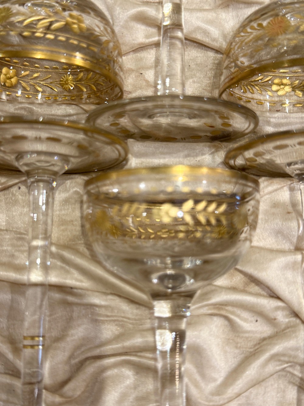 A set of twelve delicate clear glass liqueur stemware pieces with gilt decoration, resting in a padded silk-lined fitted black case. View V