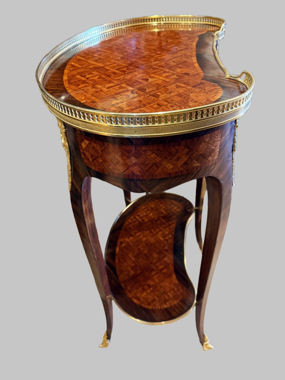 A nineteenth-century kidney-shaped side table with geometric parquetry inlay, a pierced brass gallery rim, and ormolu mounts on cabriole legs. View V