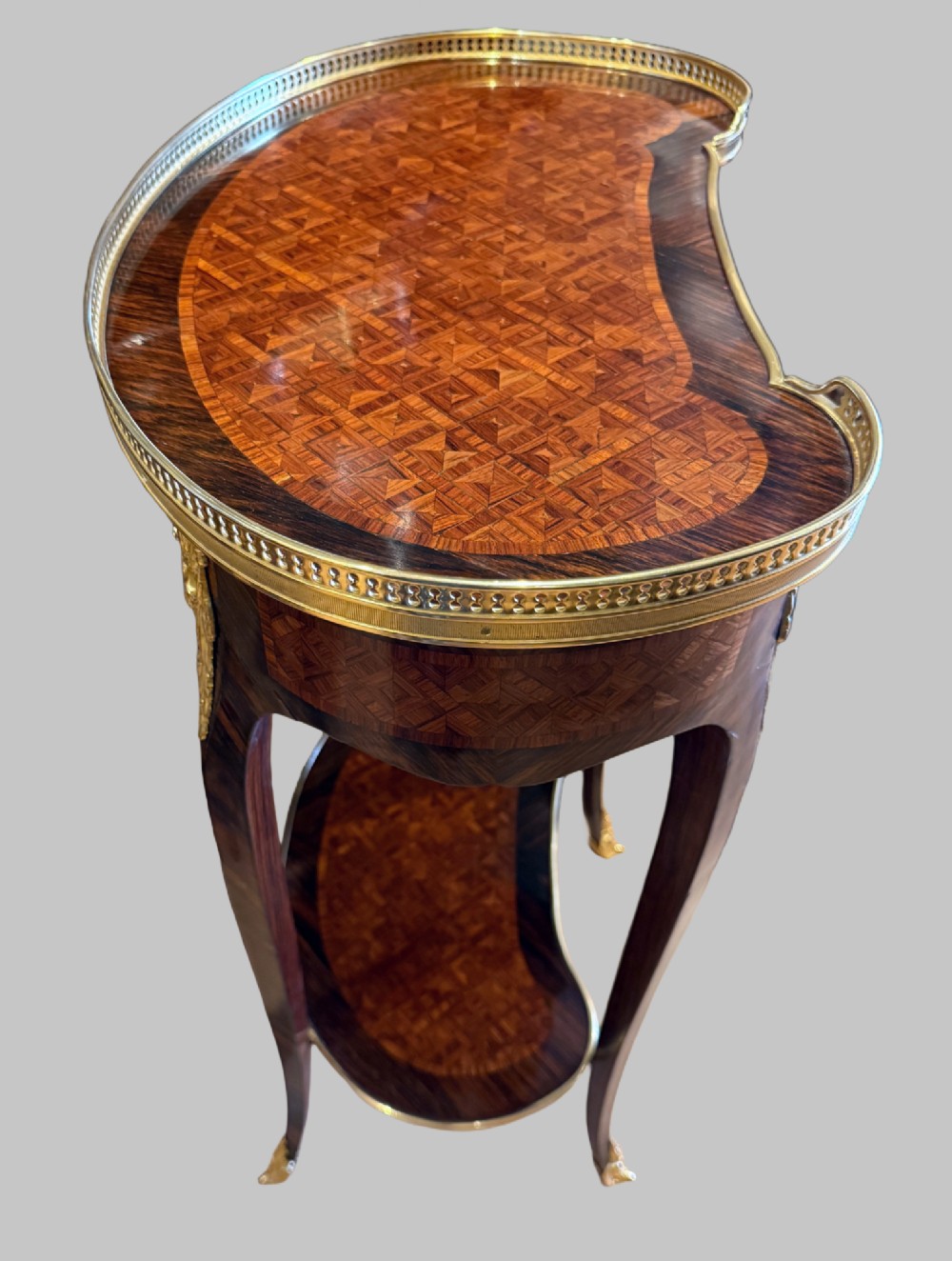 A nineteenth-century kidney-shaped side table with geometric parquetry inlay, a pierced brass gallery rim, and ormolu mounts on cabriole legs. View IX