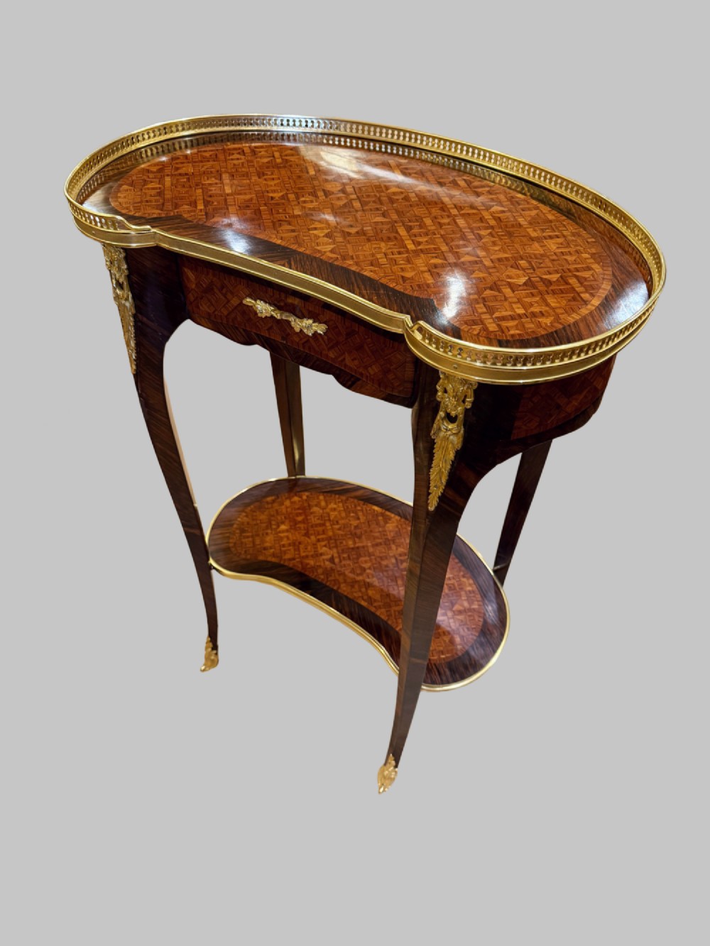 A nineteenth-century kidney-shaped side table with geometric parquetry inlay, a pierced brass gallery rim, and ormolu mounts on cabriole legs. View X