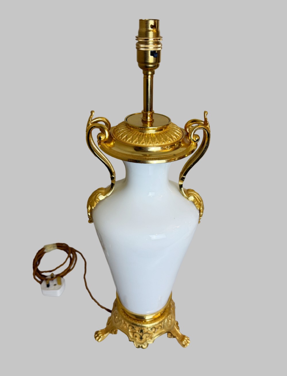 A pair of late nineteenth-century urn-shaped white glass table lamps featuring ornate gilt bronze handles, foliage mounts, and decorative cast bases. View II
