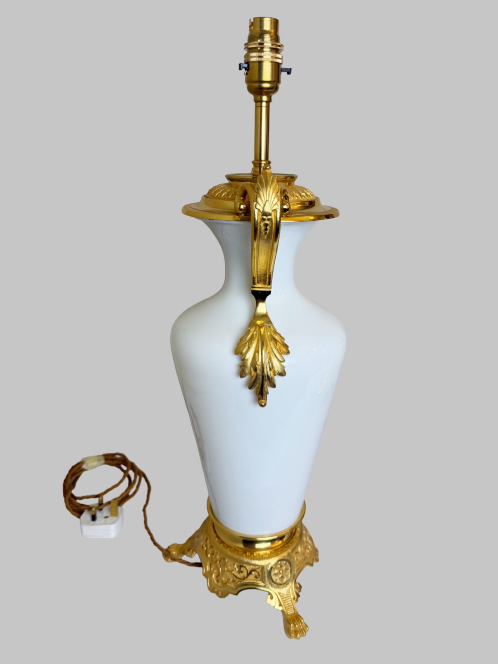 A pair of late nineteenth-century urn-shaped white glass table lamps featuring ornate gilt bronze handles, foliage mounts, and decorative cast bases. View V