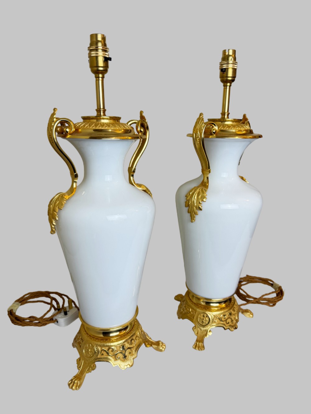 A pair of late nineteenth-century urn-shaped white glass table lamps featuring ornate gilt bronze handles, foliage mounts, and decorative cast bases. View VIII