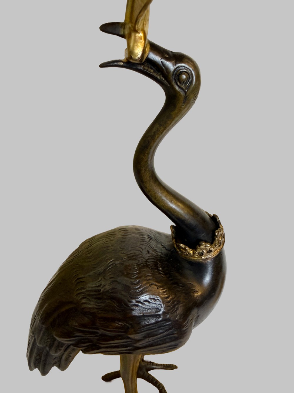 A pair of late nineteenth-century gilt and patinated bronze candlesticks featuring standing birds holding palm stems with floral candle nozzles atop rocky bases. View VI