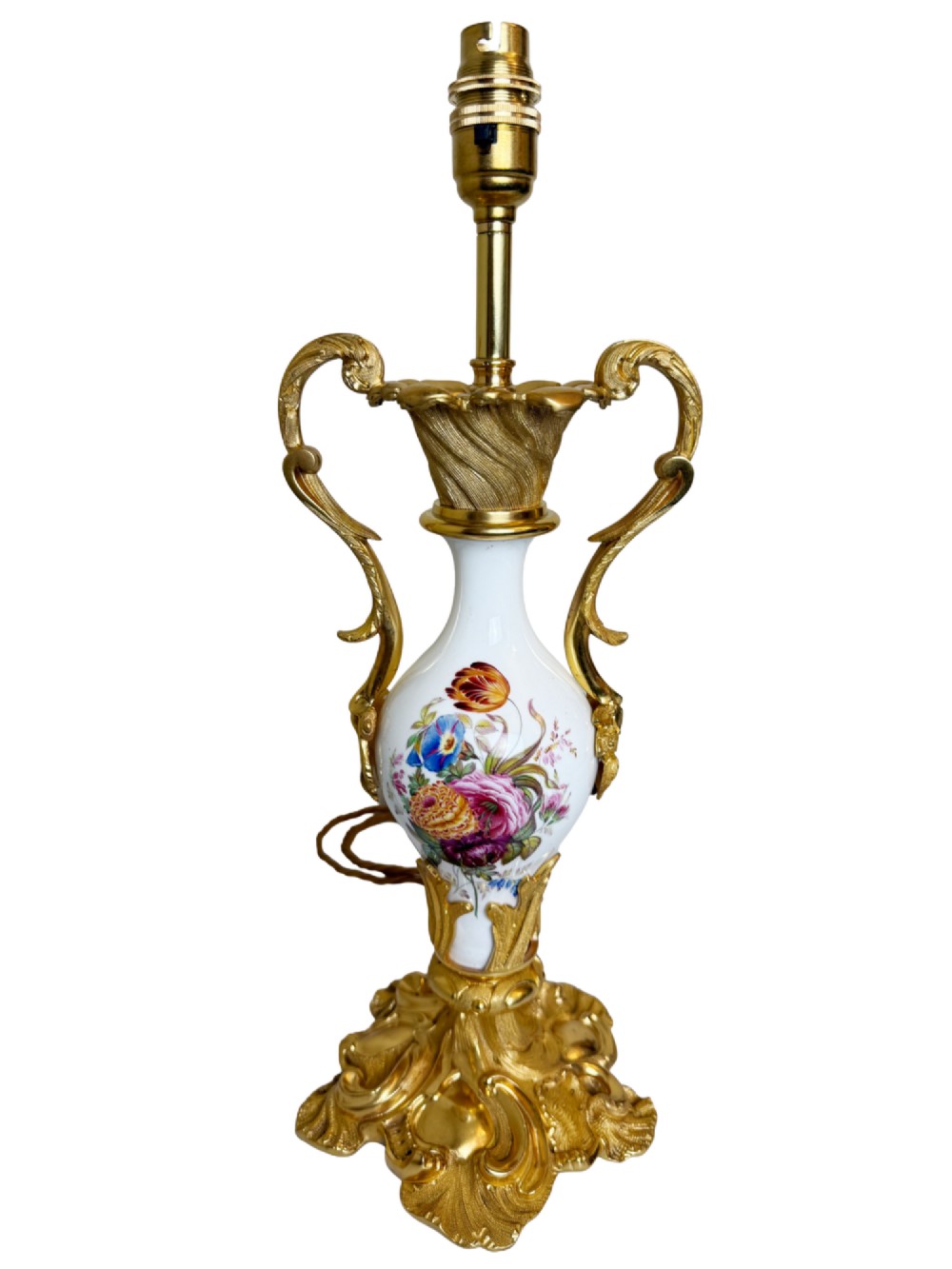 A 19th-century table lamp featuring a white porcelain urn body decorated with hand-painted flowers, set within ornate gilt bronze scroll handles and a rococo leaf base.