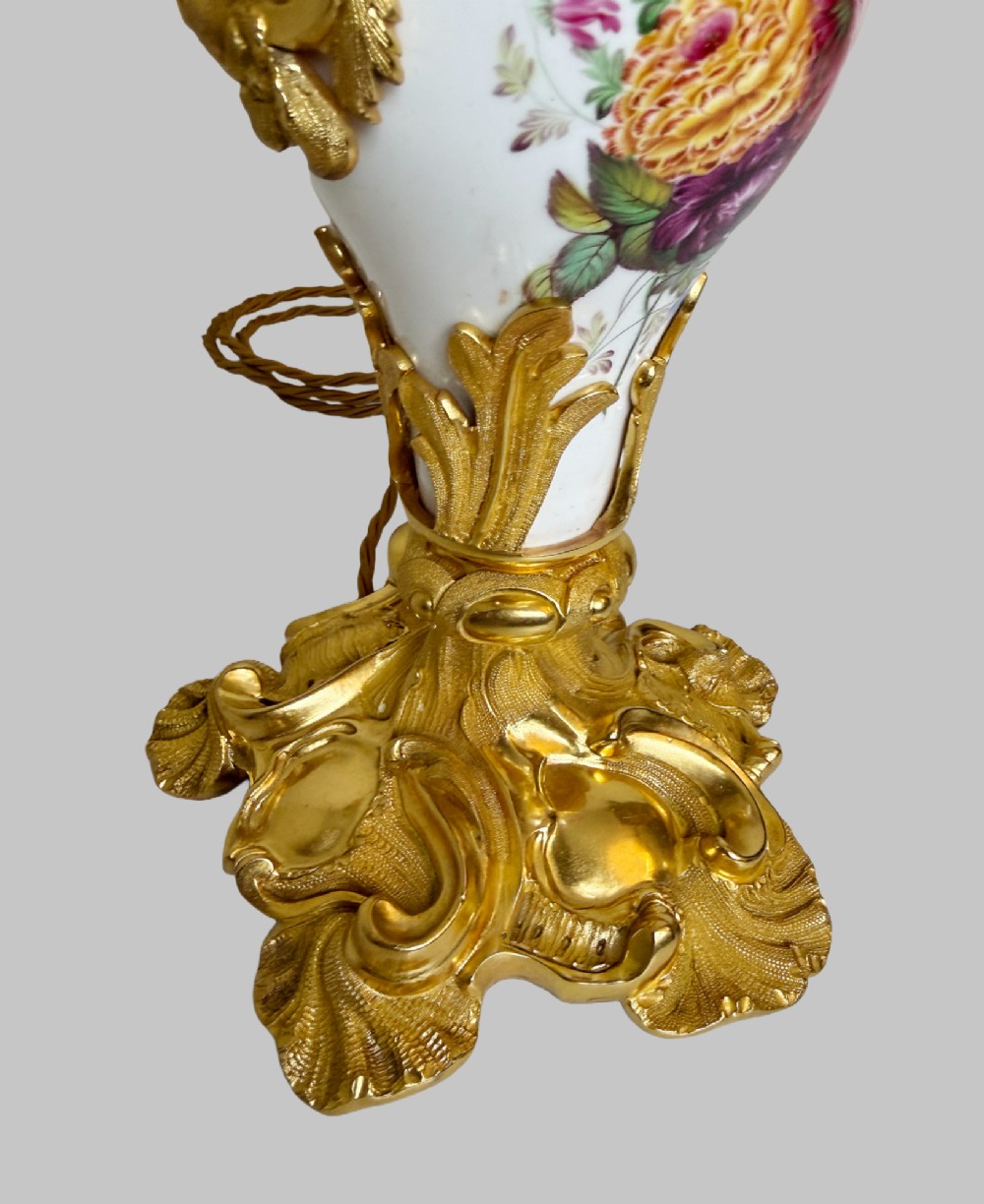 A 19th-century table lamp featuring a white porcelain urn body decorated with hand-painted flowers, set within ornate gilt bronze scroll handles and a rococo leaf base. View III