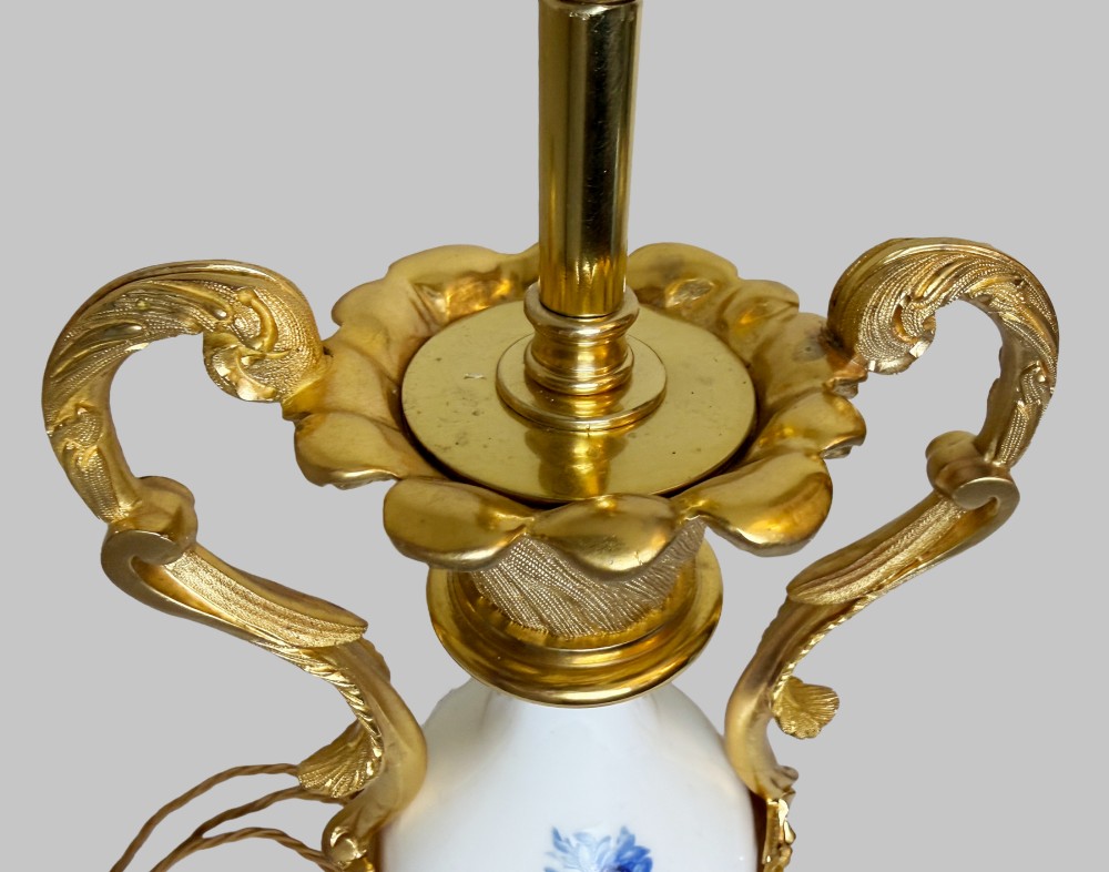 A 19th-century table lamp featuring a white porcelain urn body decorated with hand-painted flowers, set within ornate gilt bronze scroll handles and a rococo leaf base. View IV