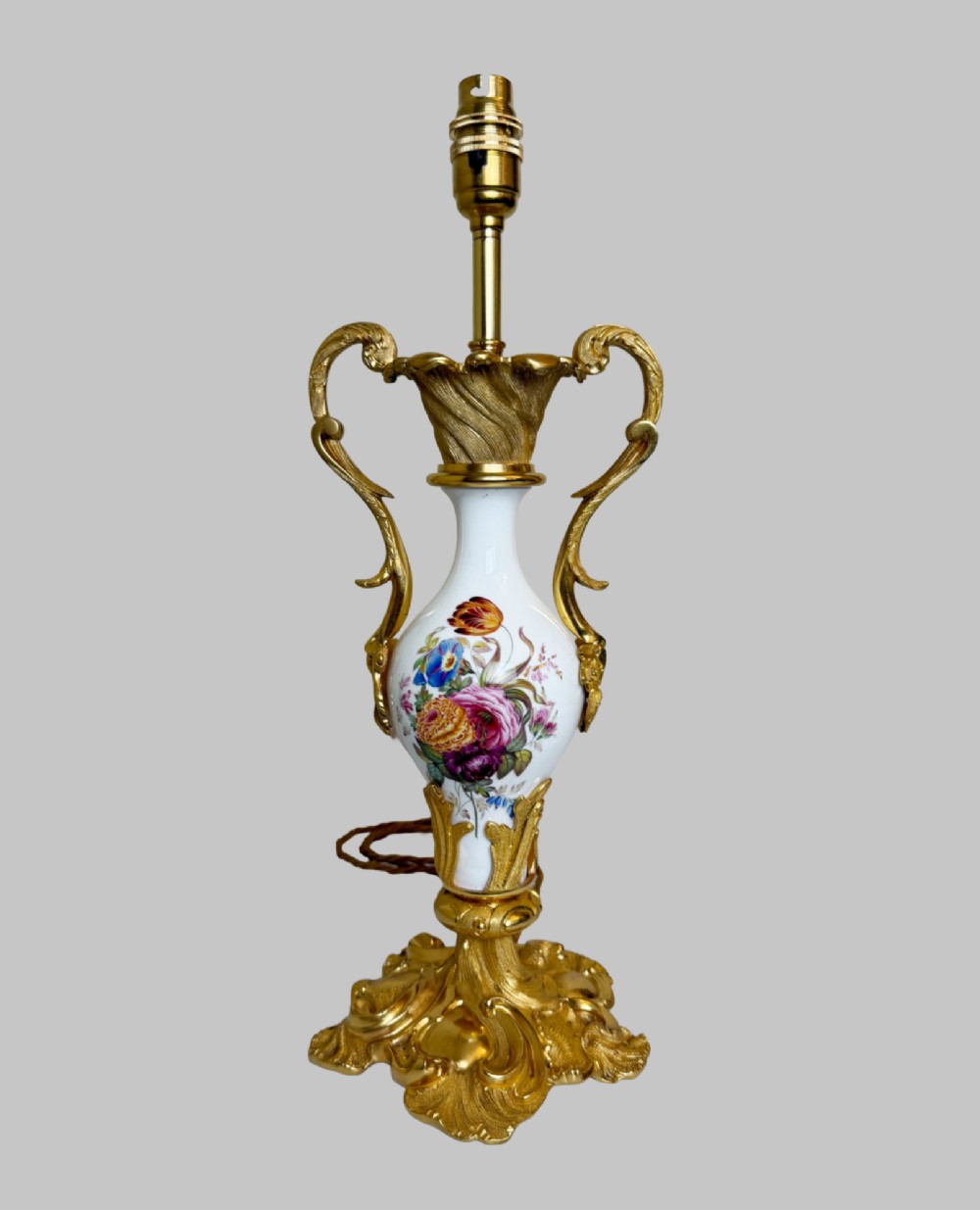 A 19th-century table lamp featuring a white porcelain urn body decorated with hand-painted flowers, set within ornate gilt bronze scroll handles and a rococo leaf base. View VII