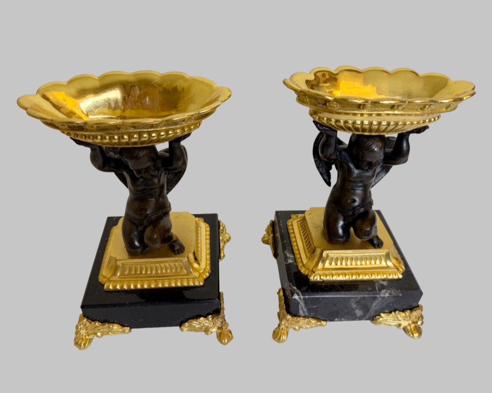 A pair of nineteenth-century gilt bronze and black marble tazzas featuring dark bronze winged cherub figures supporting fluted shallow bowls. View II