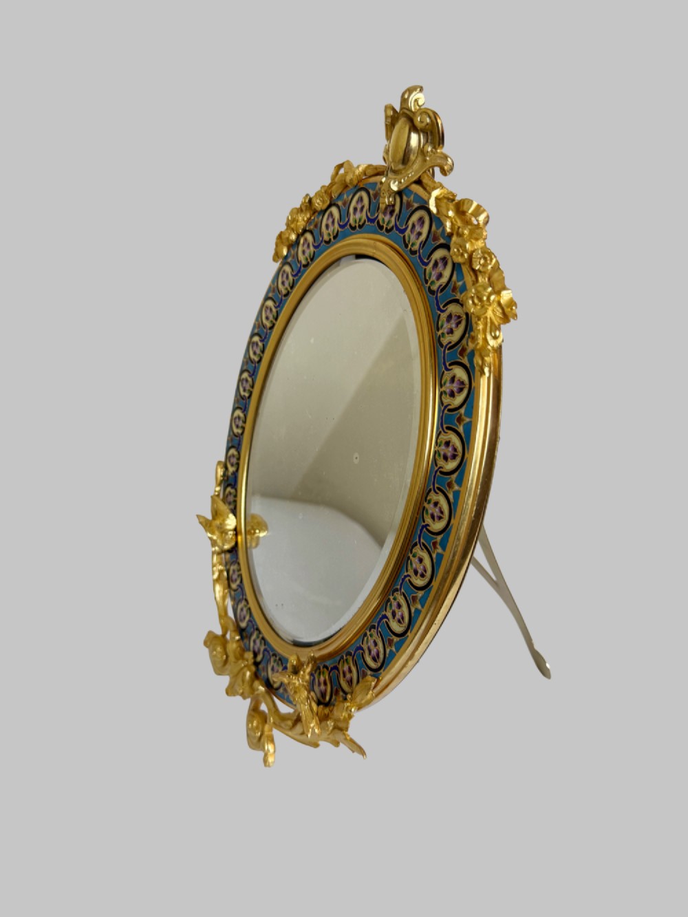 A late 19th-century oval dressing table mirror featuring a gilt bronze frame adorned with blue and purple champleve enamel and bird motifs. View III