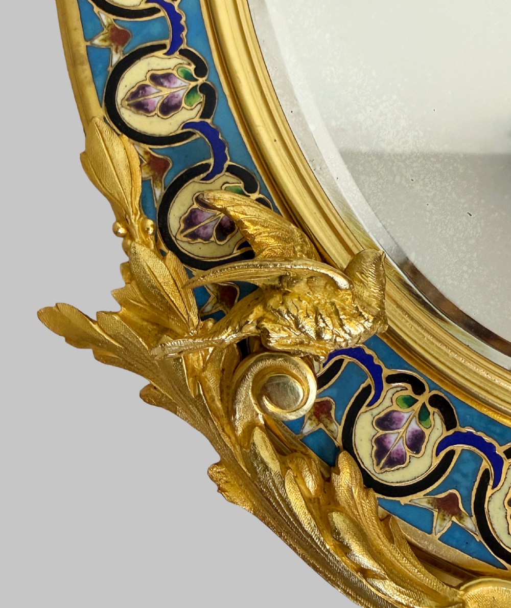 A late 19th-century oval dressing table mirror featuring a gilt bronze frame adorned with blue and purple champleve enamel and bird motifs. View VII