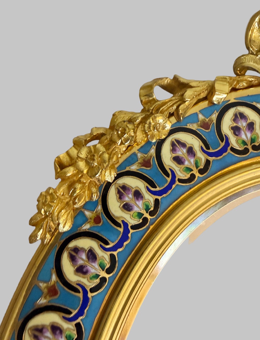 A late 19th-century oval dressing table mirror featuring a gilt bronze frame adorned with blue and purple champleve enamel and bird motifs. View IX