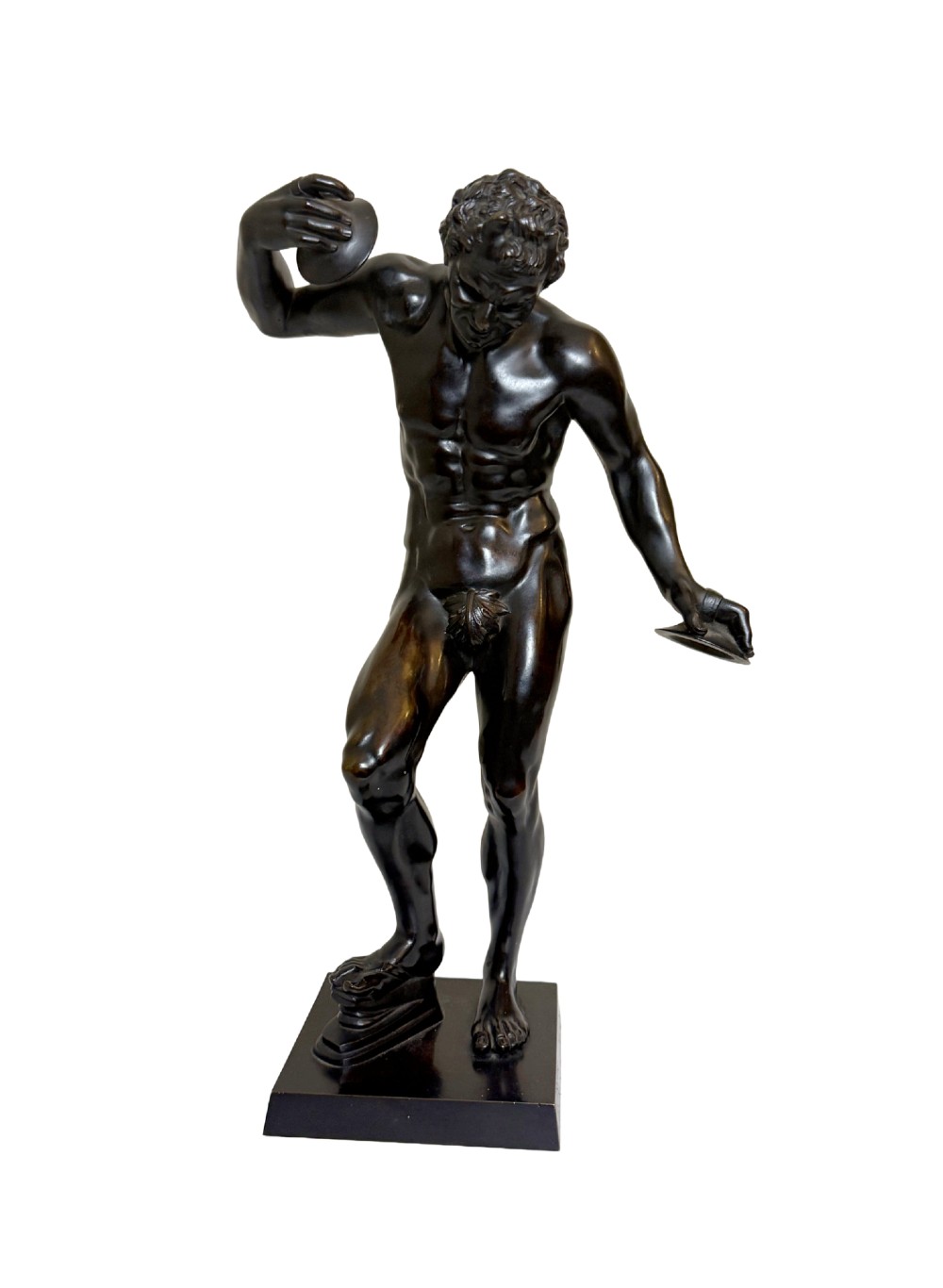 A dark patinated bronze statue depicting a nude classical dancing faun holding cymbals, mounted on a square black base.